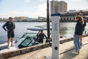 Four Candela team members talk while their boat charges on the dock