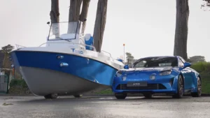 The e-tringa 700 model next to a small car of the same color, a shinty blue and white.